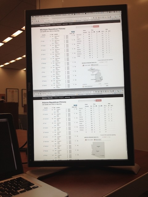 A monitor in a conference room setup in the vertical orientation